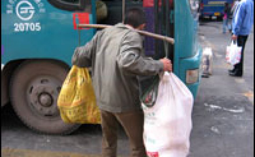 Xiong Yingkui, a "bang bang man," or porter, hauls a load at a bus stop in Chongqing.