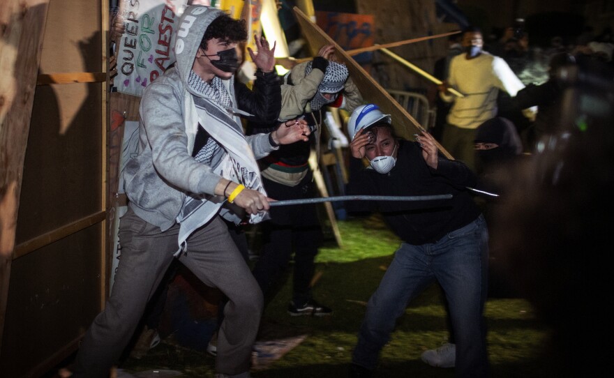 Demonstrators clash at a pro-Palestinian encampment at UCLA early Wednesday, May 1, 2024, in Los Angeles. Dueling groups of protesters have clashed at the University of California, Los Angeles, grappling in fistfights and shoving, kicking and using sticks to beat one another.