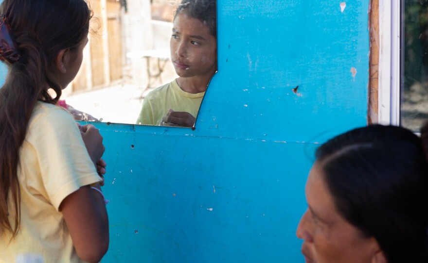 A girl from Guerrero glances in a mirror at a migrant shelter in Tijuana, Oct. 22, 2023. Her family is seeking asylum in the United States.