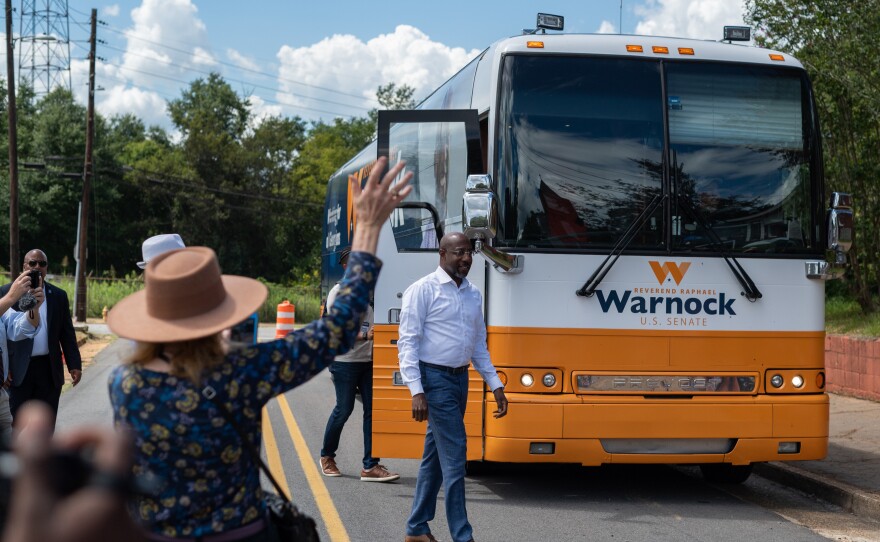 Supports cheer for U.S. Sen. Raphael Warnock outside his campaign bus in Americus, Ga.