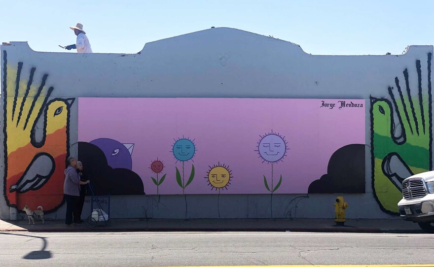 Murals in San Ysidro and near Tijuana's Instituto Municipal de Arte y Cultura (IMAC) connect seven cross-border artists and provide critical access to art to the two communities. In this September 25, 2020 photo, San Ysidro pedestrians pause in front of Jorge Mendoza's mural.