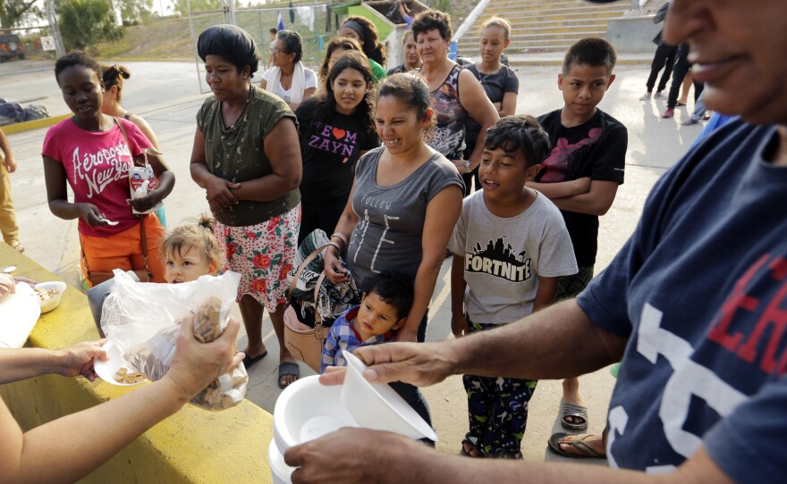 Migrants seeking asylum in the United States receive breakfast from a group of volunteers near the international bridge in Matamoros, Mexico.