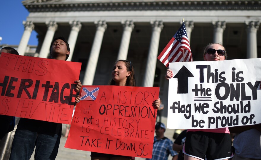 Protesters close their eyes in silent prayer as they stand on the South Carolina Statehouse steps during a rally to take down the Confederate flag, Saturday, June 20, 2015, in Columbia, S.C.
