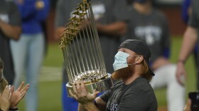 In this Tuesday, Oct. 27, 2020, file photo, Los Angeles Dodgers third baseman Justin Turner celebrates with the trophy after defeating the Tampa Bay Rays 3-1 to win the baseball World Series in Game 6 in Arlington, Texas. Turner was pulled from the game after MLB was notified that he had tested positive for COVID-19.