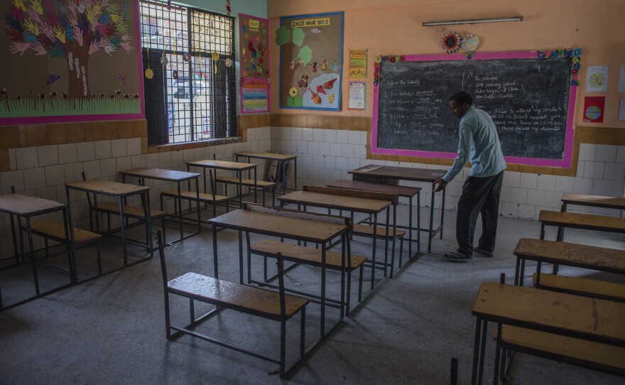 An employee adjusts desks in an empty classroom in New Delhi after schools there were closed in March. A new report finds 1 in 4 countries have either missed their planned school reopening date, or not yet set one.