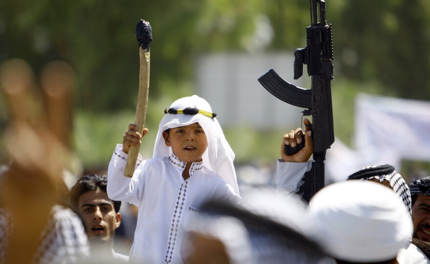 An Iraqi boy, carrying a stick amid men wielding guns, joins a demonstration in Najaf on June 14. The Shiite demonstrators were showing support for the call to arms by Iraq's top Shiite cleric, Grand Ayatollah Ali al-Sistani.