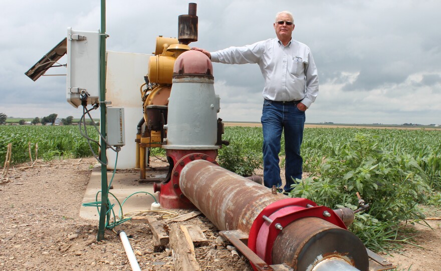 Jesse Garetson stands by one of his wells in Kansas. This one barely produces enough water to cool the engine, but many of Garetson's other wells pump more than 1,000 gallons of water per minute.