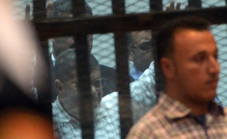 Egypt's former president Mohamed Morsi gestures from the defendants' cage during his trial at a court in Cairo, Tuesday. An Egyptian court sentenced the ousted leader to 20 years in prison over abuses of protesters.