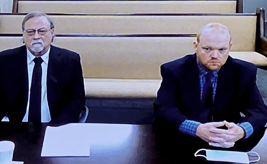 In this image made from video, from left, father and son, Gregory and Travis McMichael, accused in the shooting death of Ahmaud Arbery, listen via closed circuit TV in the Glynn County Detention center in Brunswick, Ga., on Nov. 12.