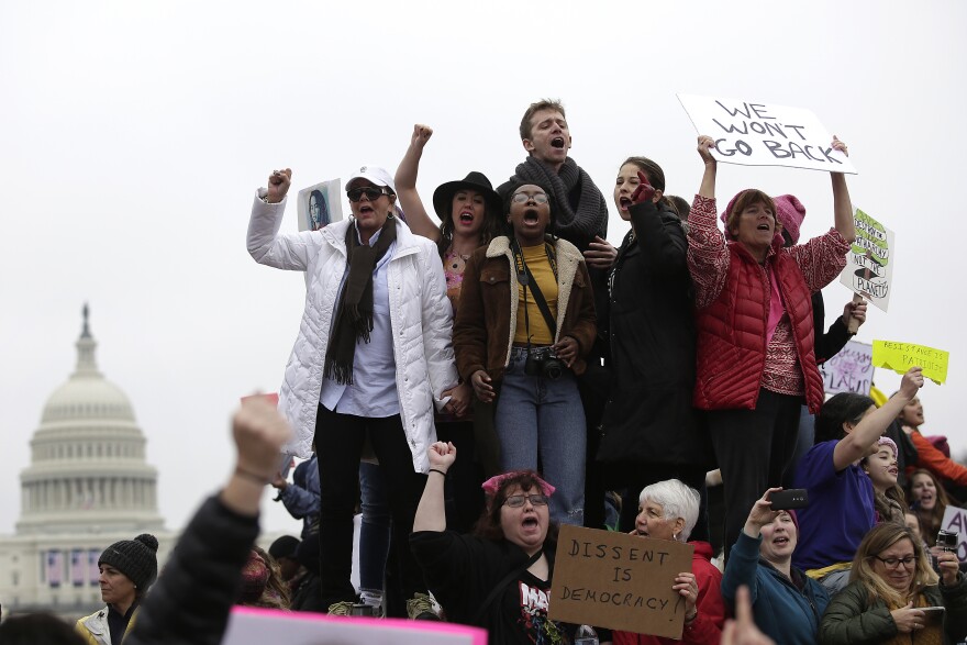 Protesters march in Washington, D.C., with the Capitol in the background.
