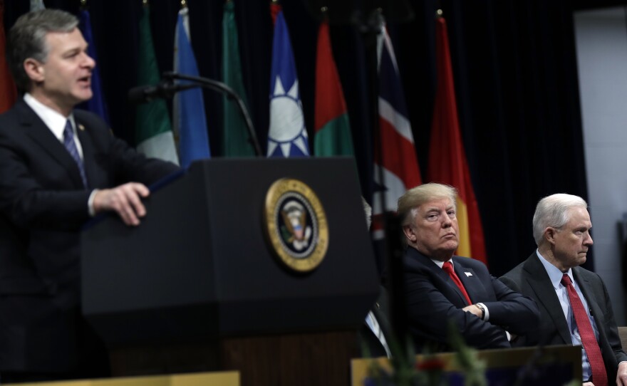 President Donald Trump, listens to FBI Director Christopher Wray speak, with Attorney General Jeff Sessions (right) at the FBI National Academy graduation ceremony on Friday, in Quantico, Va.