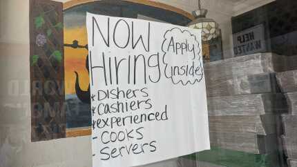 A "now hiring" sign hangs in the window of Filipe's Pizza in Escondido, Calif. Aug. 9, 2021.