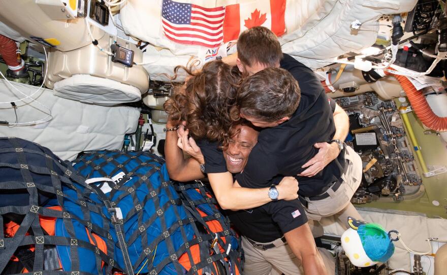 The Artemis II astronauts share a group hug aboard the Orion capsule.