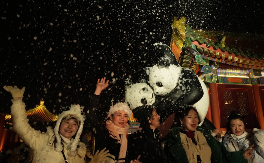 Attendees at an event that coincided with New Year's Eve cheer as fake snow from a foam machine is blown overhead in Beijing on Friday.