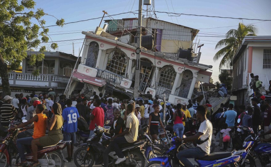 <strong>Sat., Aug. 14:</strong> People gather outside the Petit Pas Hotel, destroyed by the earthquake in Les Cayes, Haiti.