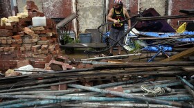 Adrian Bentancourt cleans up debris from a fence that was blow down by Hurricane Nicholas Tuesday, Sept. 14, 2021, in Galveston, Texas. 
