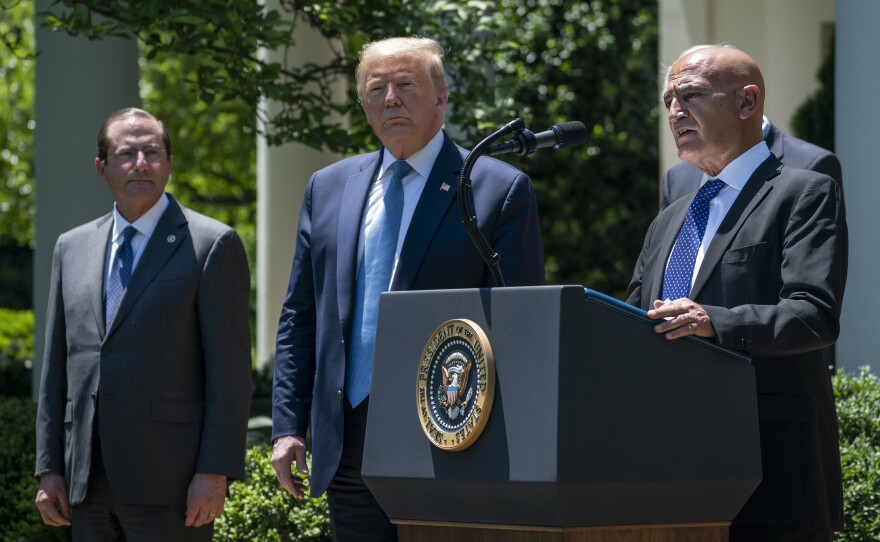 Then-Health and Human Services Secretary Alex Azar (left) and President Donald Trump listen as Moncef Slaoui of Operation Warp Speed speaks about the crash program to develop a COVID-19 vaccine in the White House Rose Garden on May 15, 2020.