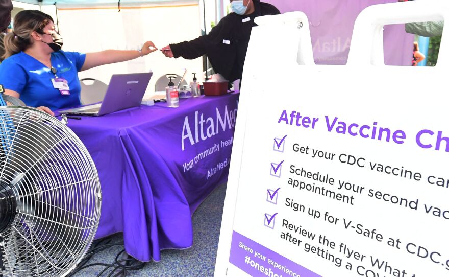 A nurse from AltaMed Health Services hands out the vaccine card to people after receiving their Covid-19 vaccine in Los Angeles, California on August 17, 2021.