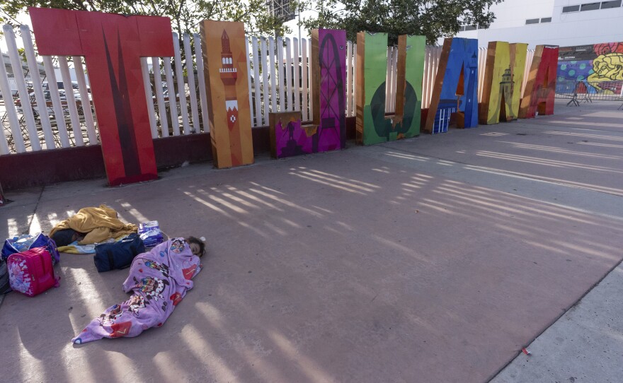 A girl from the Mexican state of Morelia sleeps in front of a sign for Tijuana as her family's CBP One application appointments to apply for asylum in the United States were declared not valid on the application Monday, Jan. 20, 2025, in Tijuana, Mexico, shortly after President Donald Trump was sworn-in.