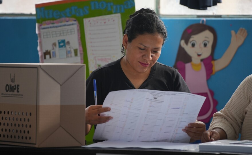 An election official checks voter lists as voting resumes at polling stations affected by delays and logistical problems during general elections in Lima, Peru, Monday, April 13, 2026.