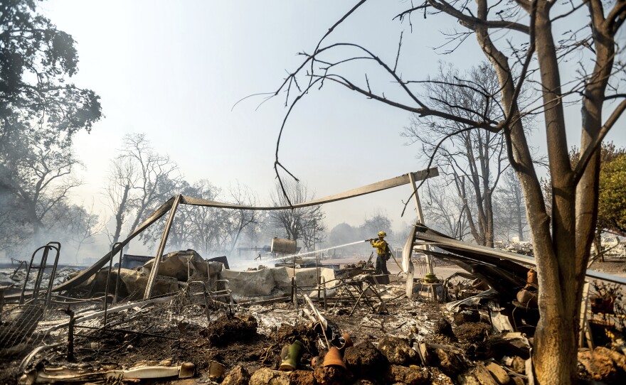 Firefighter Cory Souza sprays water at Cache Creek Mobile Home Estates where the Cache Fire leveled dozens of residences on Wednesday, Aug. 18, 2021, in Clearlake, Calif.