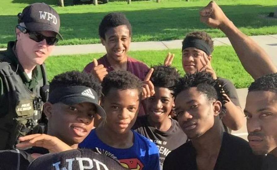 Officers pose with young men on a basketball court during a community cookout in Wichita, Kan.