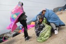 A family from Peru tries to stay warm under blankets while waiting to be processed by immigration authorities near Boulevard, Jan 3. 2023.