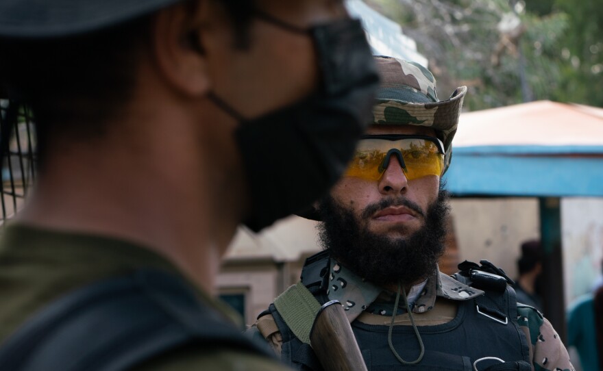 A Taliban guard (right) stands adjacent to a Pakistani guard at the Torkham border crossing.