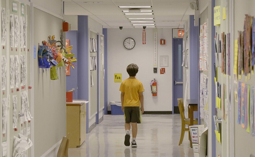 A student walks down a school hallway.