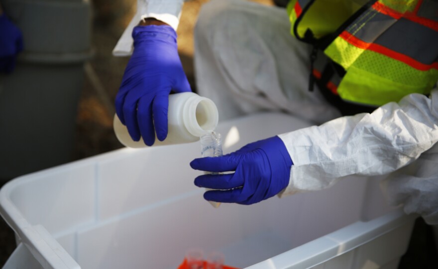 A CSU graduate student fills test tubes with wastewater samples outside Westfall Hall.