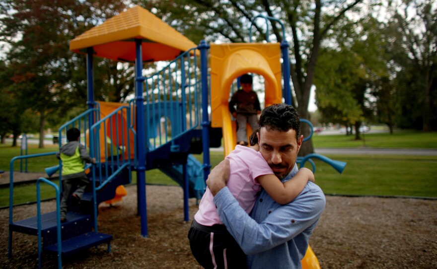 Omar holds his daughter, Taiba, at the playground near the family's new home in Toledo.