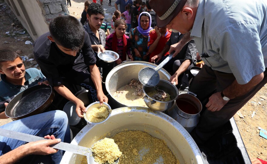 Iraqi Yazidi families who fled the violence in their home town of Sinjar are given food at a school where they are taking shelter in the Kurdish city of Dohuk on Tuesday.