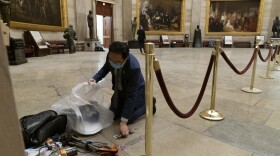 Rep. Andy Kim, D-N.J., cleans up debris and personal belongings strewn across the floor of the Rotunda in the early morning hours of Thursday, Jan. 7, 2021, after protesters stormed the Capitol in Washington, on Wednesday. 