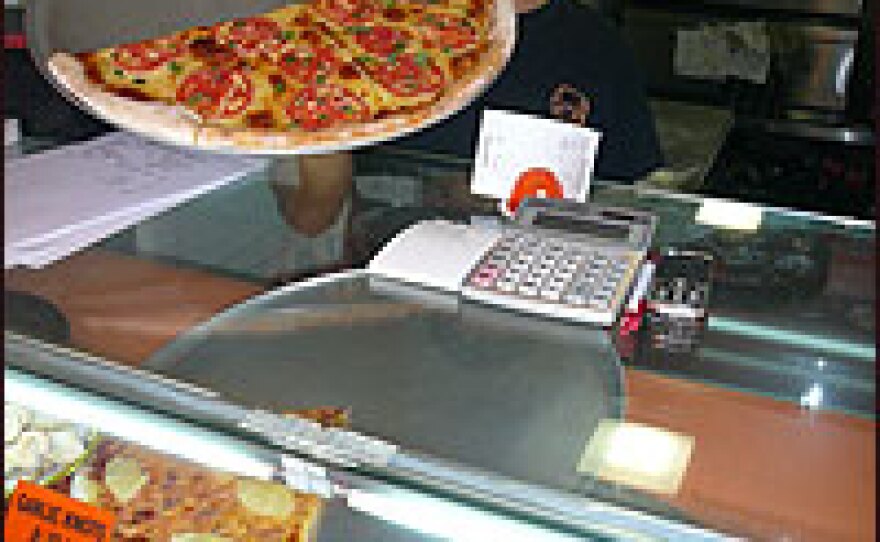 A shopkeeper displays his wares at Shanghai's "New York Pizza Parlor." The shop sells around 50 large pizzas every day; the increasing popularity of Western food means China's 1.3 billion residents are consuming more milk than before.