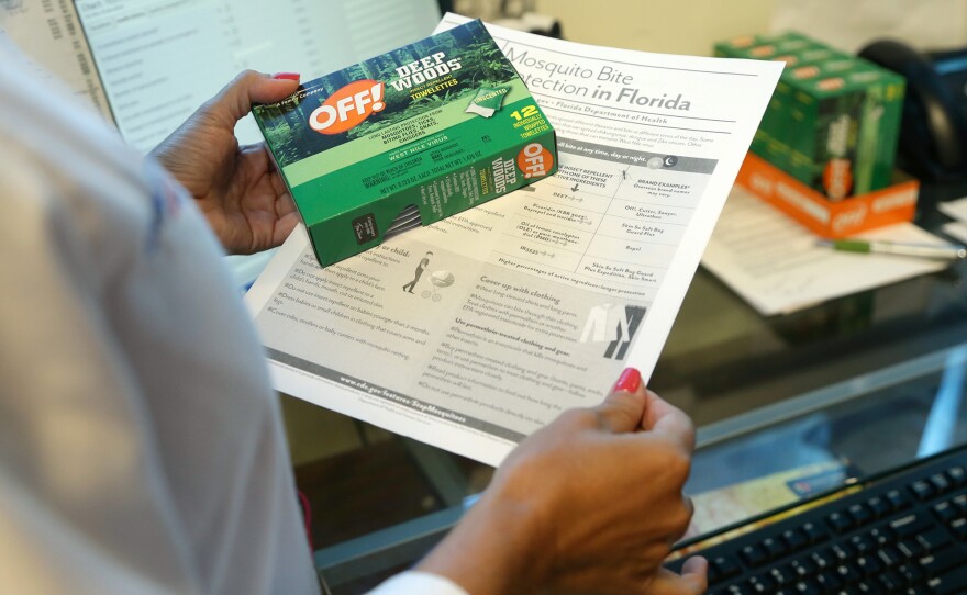 Nurse practitioner Juliana Duque holds a box of insect repellent and information on mosquito protection for pregnant patients at the Borinquen Medical Center in Miami.