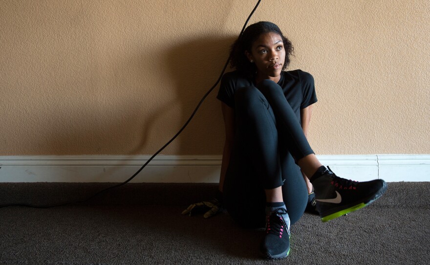 (Top left) Vashti Cunningham does lunges as her father vacuums in the garage, which functions as a training room at the Cunninghams' home in Las Vegas. (Top right) A poster of Cunningham peeks over storage boxes in the garage at the Cunninghams' home. (Bottom) Cunningham stretches as she begins a workout with her father.