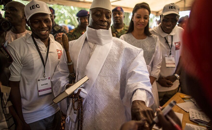 Incumbent Gambian President Yahya Jammeh (center) has his finger inked before casting his marble in a polling station during the presidential election.