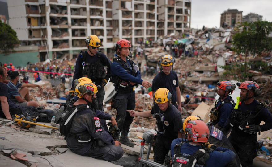 Member of the Los Angeles County Fire Department stand on rubble of a collapsed building in La Guaira, Venezuela, Tuesday.
