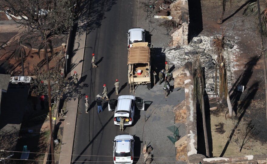 In an aerial view, search and rescue crews walk through a neighborhood that was destroyed by a wildfire on August 11, 2023 in Lahaina, Hawaii. Conspiracy theories about the fire quickly centered on anti-government narratives or stories about wealthy people seeking more land for development.