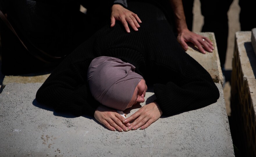 A woman mourns on the grave of her husband during the funeral of 13 state security officers killed the previous day in an Israeli strike in Lebanon's coastal city of Sidon, Saturday, April 11, 2026.