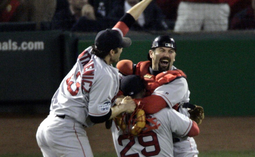 Boston Red Sox's Doug Mientkiewicz, left, and catcher Jason Varitek, right, jump into Keith Foulke's arms after the Red Sox defeated the St. Louis Caridnals 3-0 in Game 4 to win the 2004 World Series.