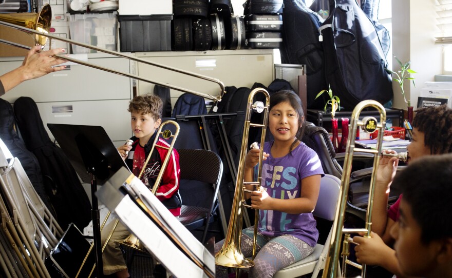 Esmeralda Martinez, center, demonstrates good trombone posture. Her practice room is an office and storage room by day which requires the kids to squeeze in between filing cabinets, folding chairs and stacked instruments.