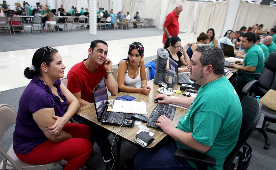 Yudelmy Cataneda, Javier Suarez and Claudia Suarez talk with insurance agent Yosmay Valdivian at a session to sign up for health insurance in a Miami mall March 20.