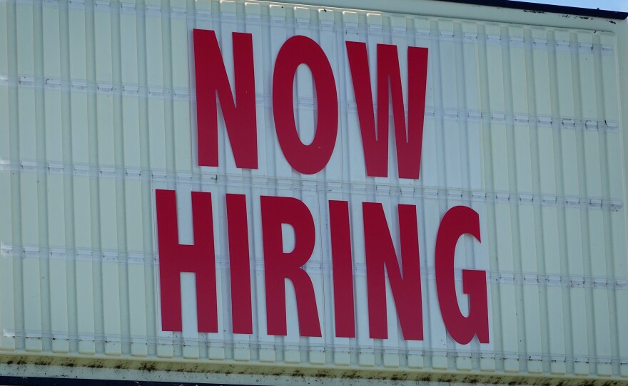 A 'Now Hiring' sign hangs in front of a Winn-Dixie grocery store in Miami on Dec. 3. Omicron is spreading at a time when some businesses such as restaurants are already strugging to find workers.