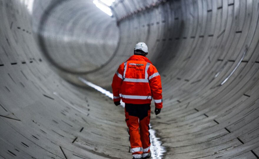 Construction worker inspects completed tunnel beneath the Thames, London, England. (undated photo)