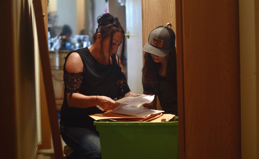 As her daughter Daisyauna watches, Daisy Hohman sifts through paperwork from the time her children were placed in foster care. Hohman says having to pay her Minnesota county was an added stress in her life: "This is the money I live on for me and my children."