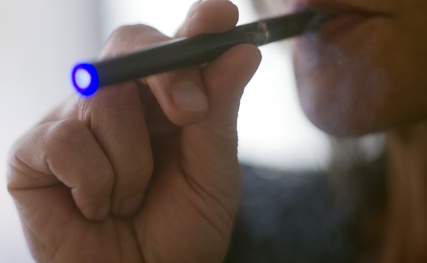 Photo illustration of a woman smoking an e-cigarette.