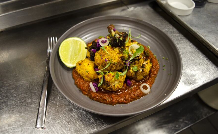 Onwuachi's life story is written in his recipes. Here, a plate of charred brassicas, served with Nigerian red sauce.