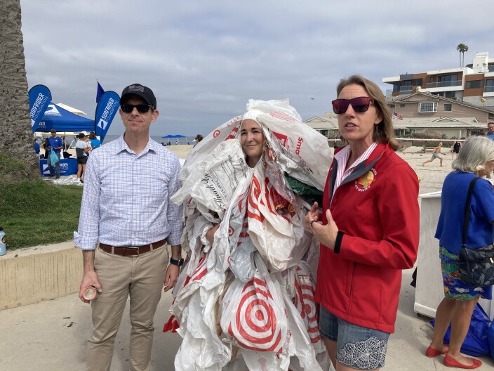 Jessica Ullyott — the bag monster — stands with Congressman Mike Levin and California State Senator Catherine Blakespeare at an environmental rally at Moonlight Beach in Encinitas. Aug. 17, 2024