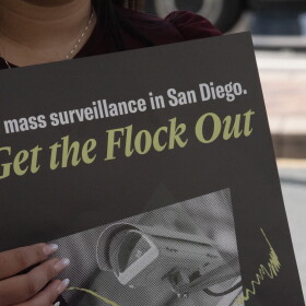A protester holds a sign at a press conference announcing a lawsuit over the city of San Diego's use of Automated License Plate Reader technology on Sept. 30, 2026.